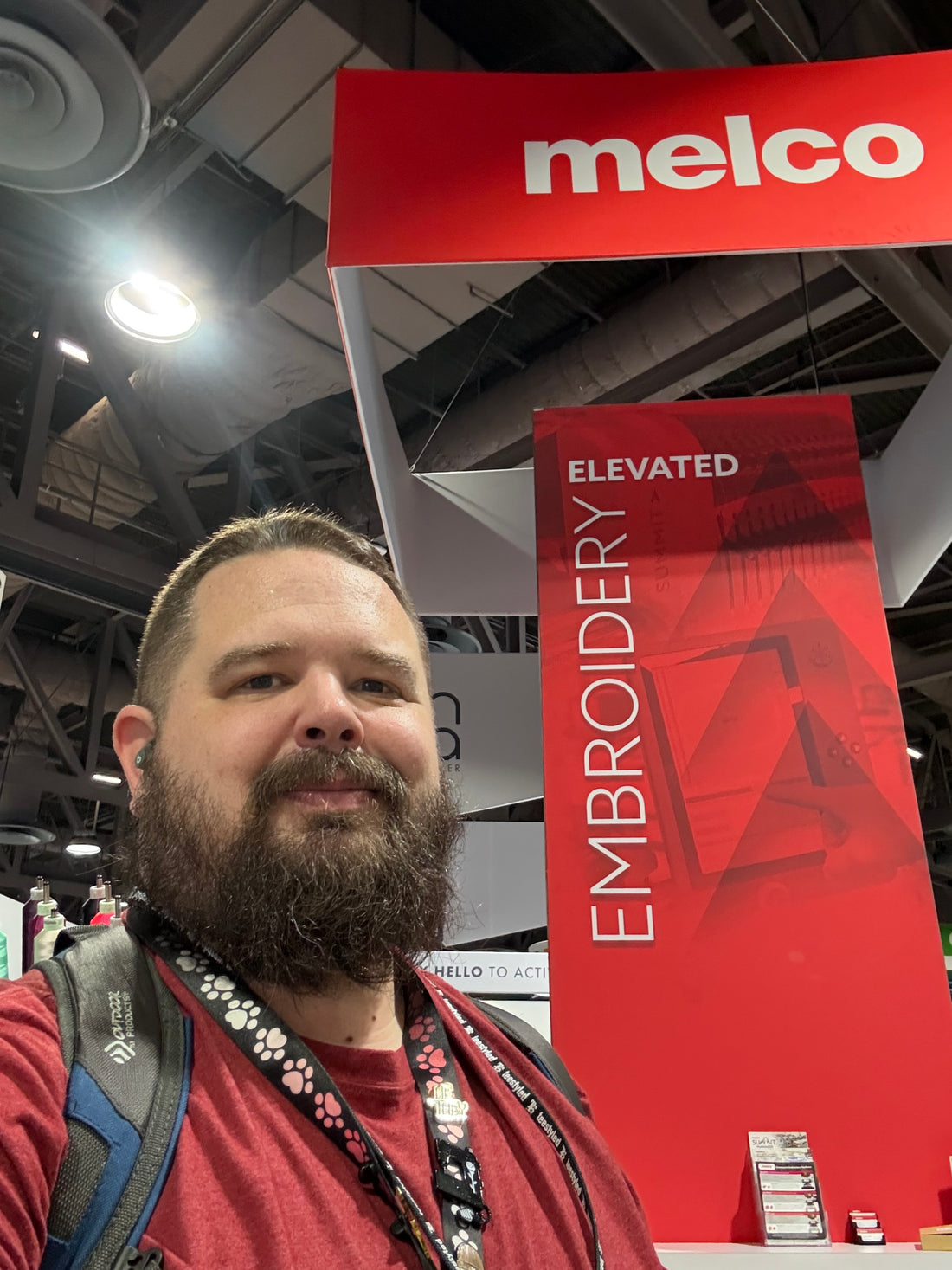 bearded man in front of a trade show booth for Melco