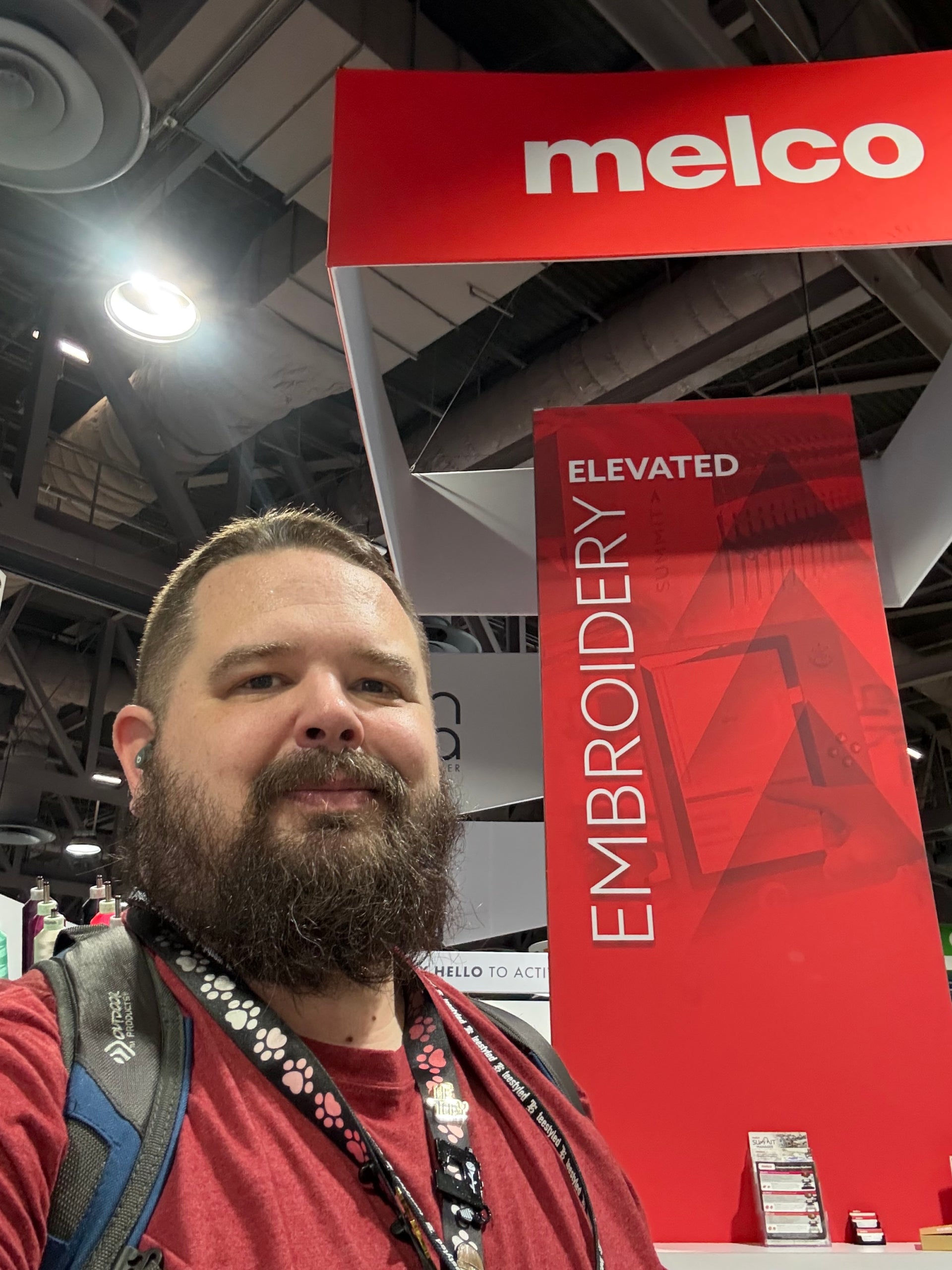 bearded man in front of a trade show booth for Melco