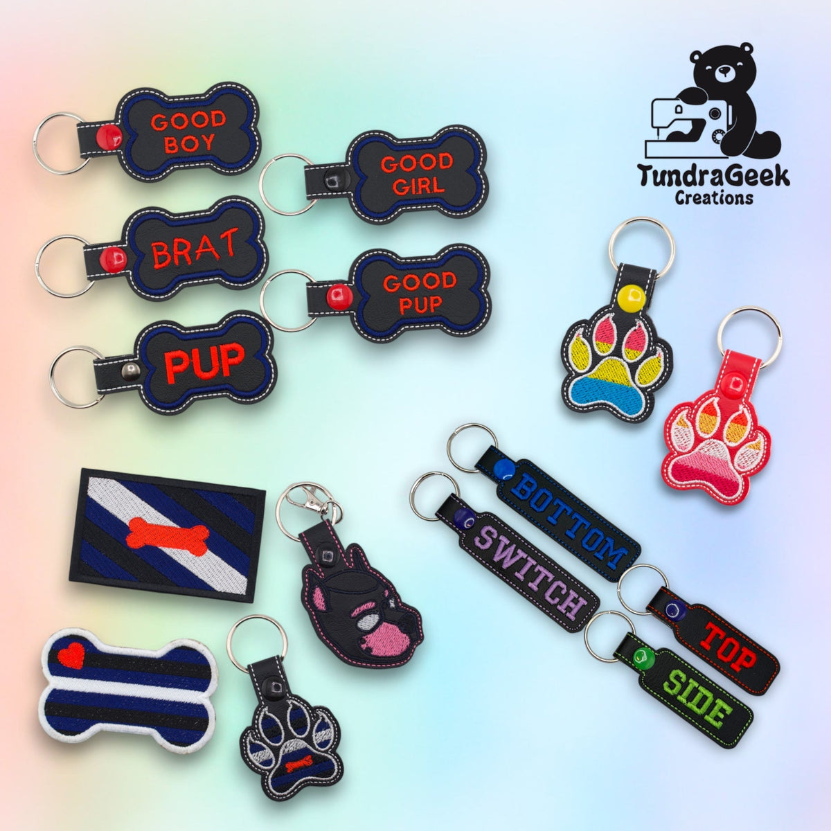 A group of embroidered vinyl keychains and patches on a pastel background, including bone-shaped tags reading Good Boy, Good Girl, Brat, Good Pup and Pup, paw-shaped keychains in pride flag colors, and bar tags reading Top, Bottom, Switch and Side.