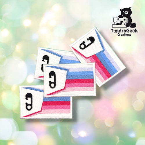 Four ABDL pride patches grouped together, each showing the same waving flag design with a black diaper pin icon on white satin.