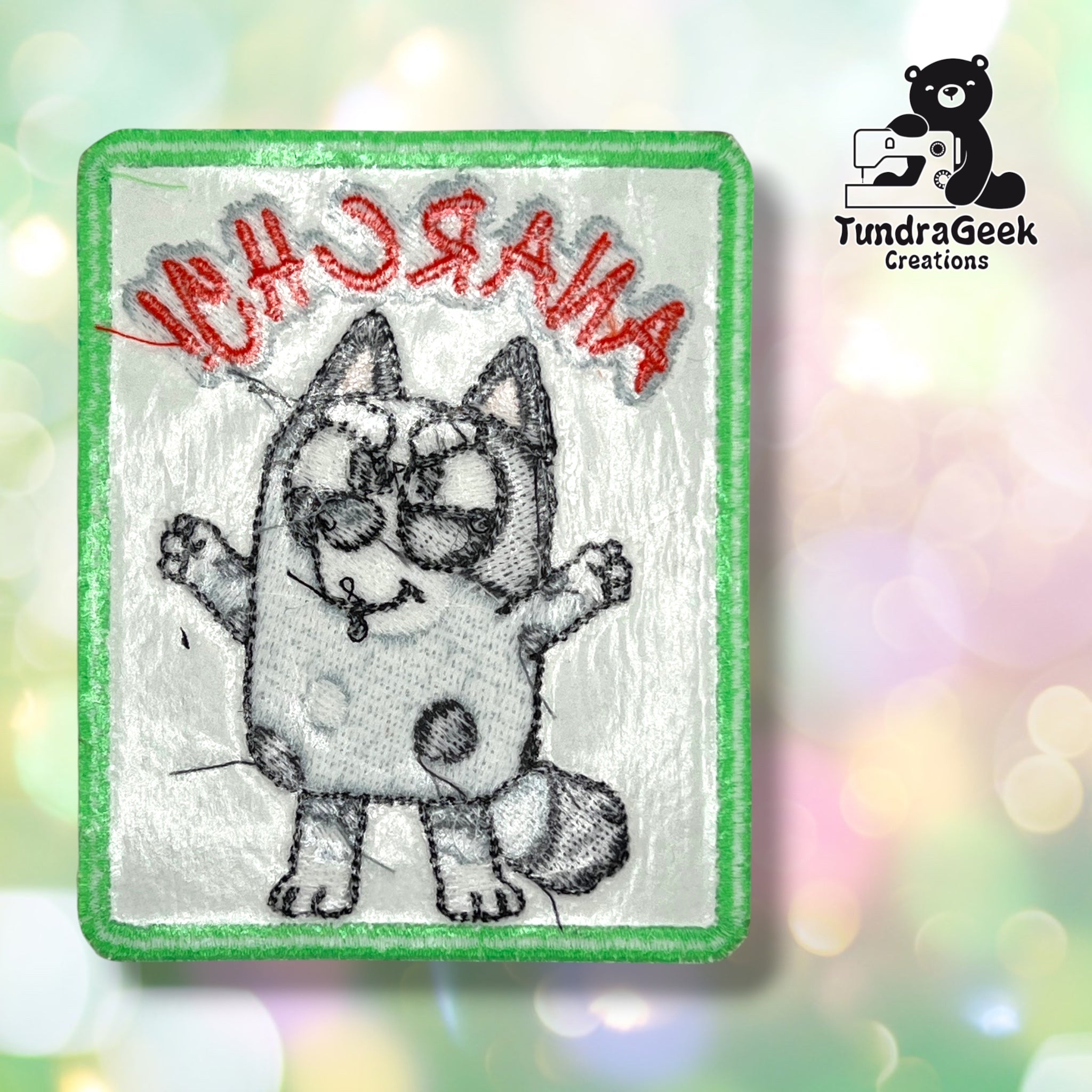 Embroidered patch with a cartoon cat and the word ANARCHY stitched in red, upside down. Logo for TundraGeek Creations and a sewing bear icon appear in the background.
