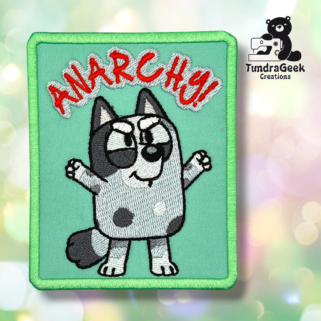 Embroidered patch of a cartoon dog with raised arms, text ANARCHY! in red above, and TundraGeek Creations logo in the corner.