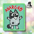 Embroidered patch of a cartoon dog with raised arms, text ANARCHY! in red above, and TundraGeek Creations logo in the corner.