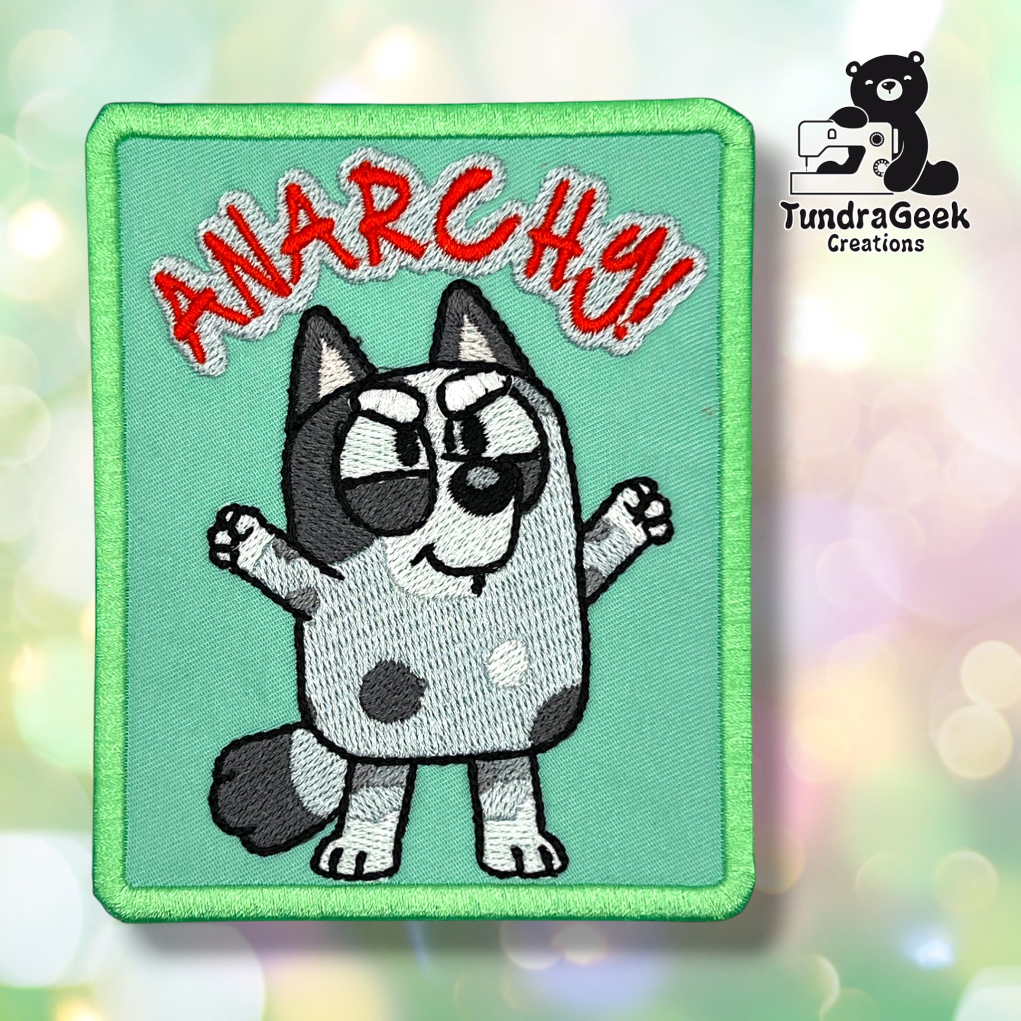 Embroidered patch of a cartoon dog with raised arms, text ANARCHY! in red above, and TundraGeek Creations logo in the corner.
