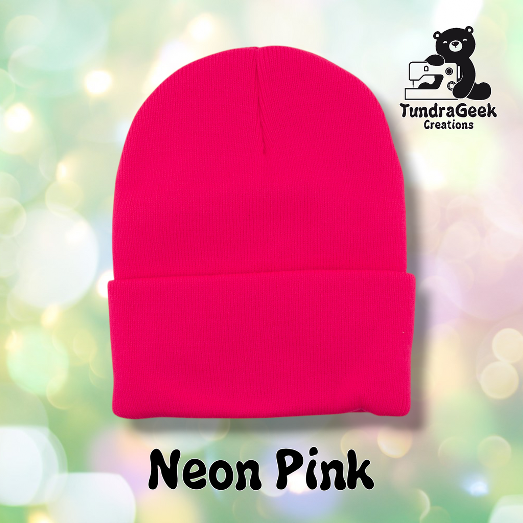 Plain neon pink cuffed beanie on a pastel bokeh background. Text reads "Neon Pink" at the bottom of the image.