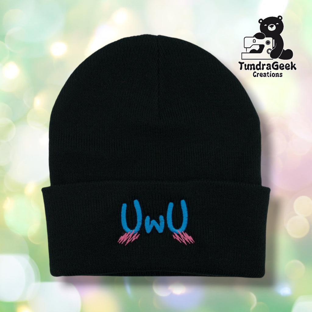 lack cuffed acrylic beanie with "UwU" embroidered in blue on the cuff. Pink blush marks are embroidered beneath the text. TundraGeek Creations logo in upper right corner.
