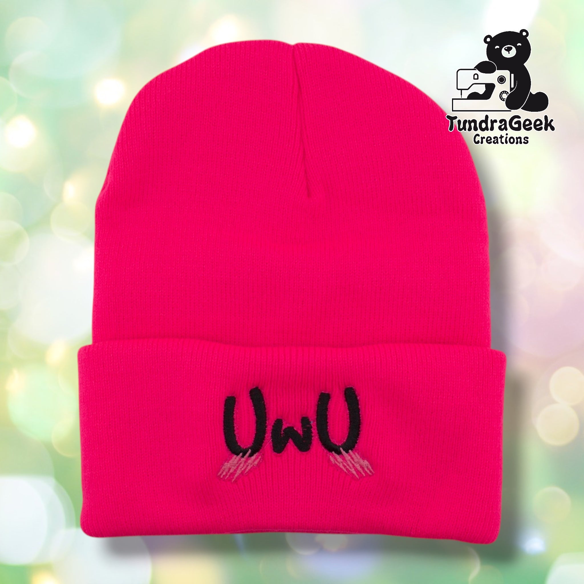 Neon pink cuffed acrylic beanie with "UwU" embroidered in black on the cuff. Pink blush marks are embroidered beneath the text. TundraGeek Creations logo in upper right corner.