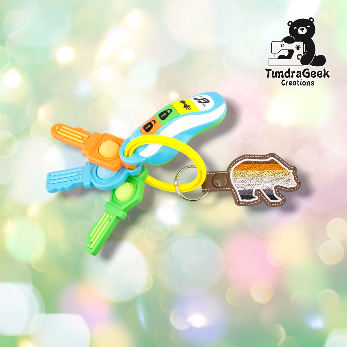 Bear-Shaped Bear Pride keychain attached to a set of colorful toy keys, showing the keychain in use on a ring alongside other charms.