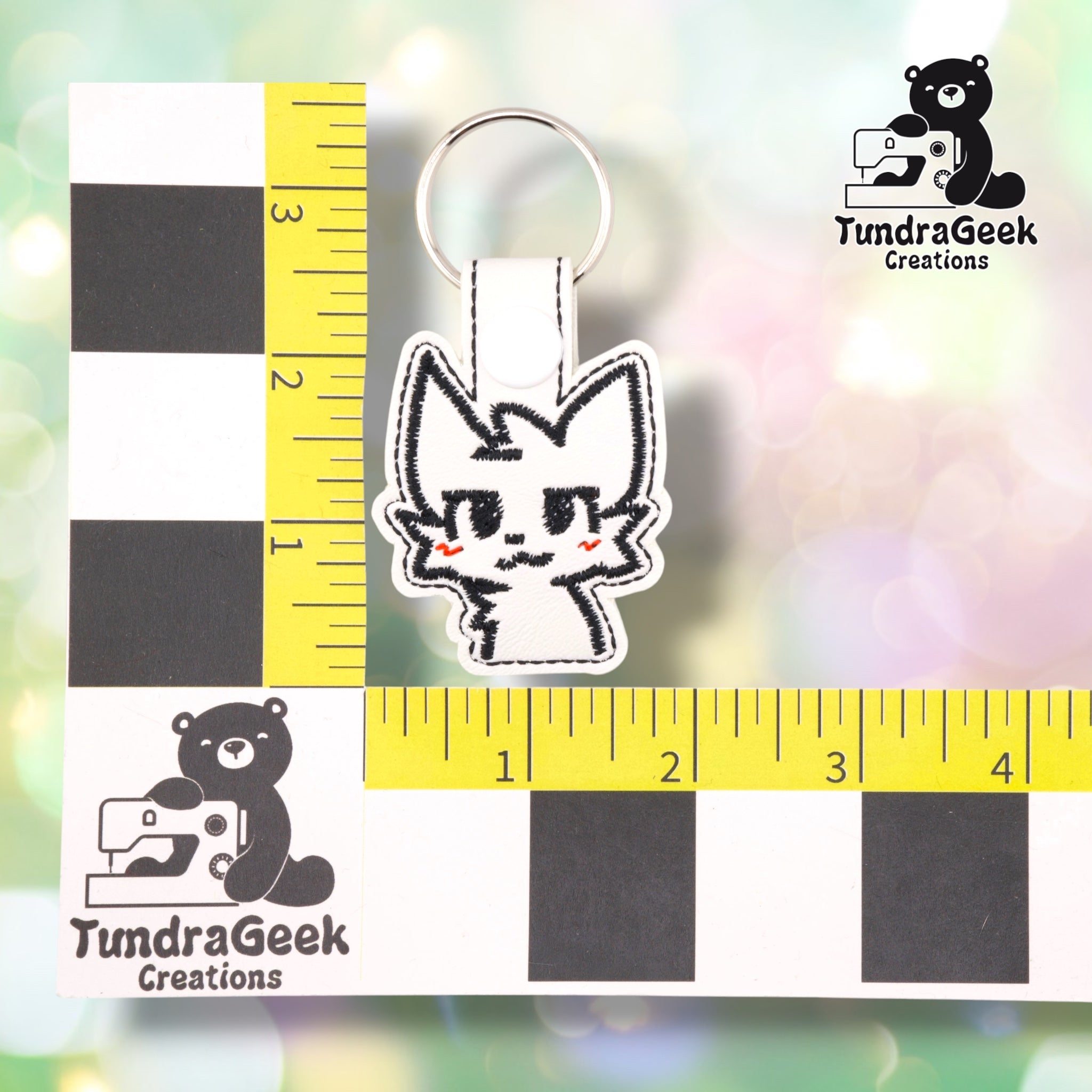 Boykisser keychain shown against a TundraGeek Creations ruler prop, confirming approximately 1.75in wide by 3.5in tall, including hardware.  ---