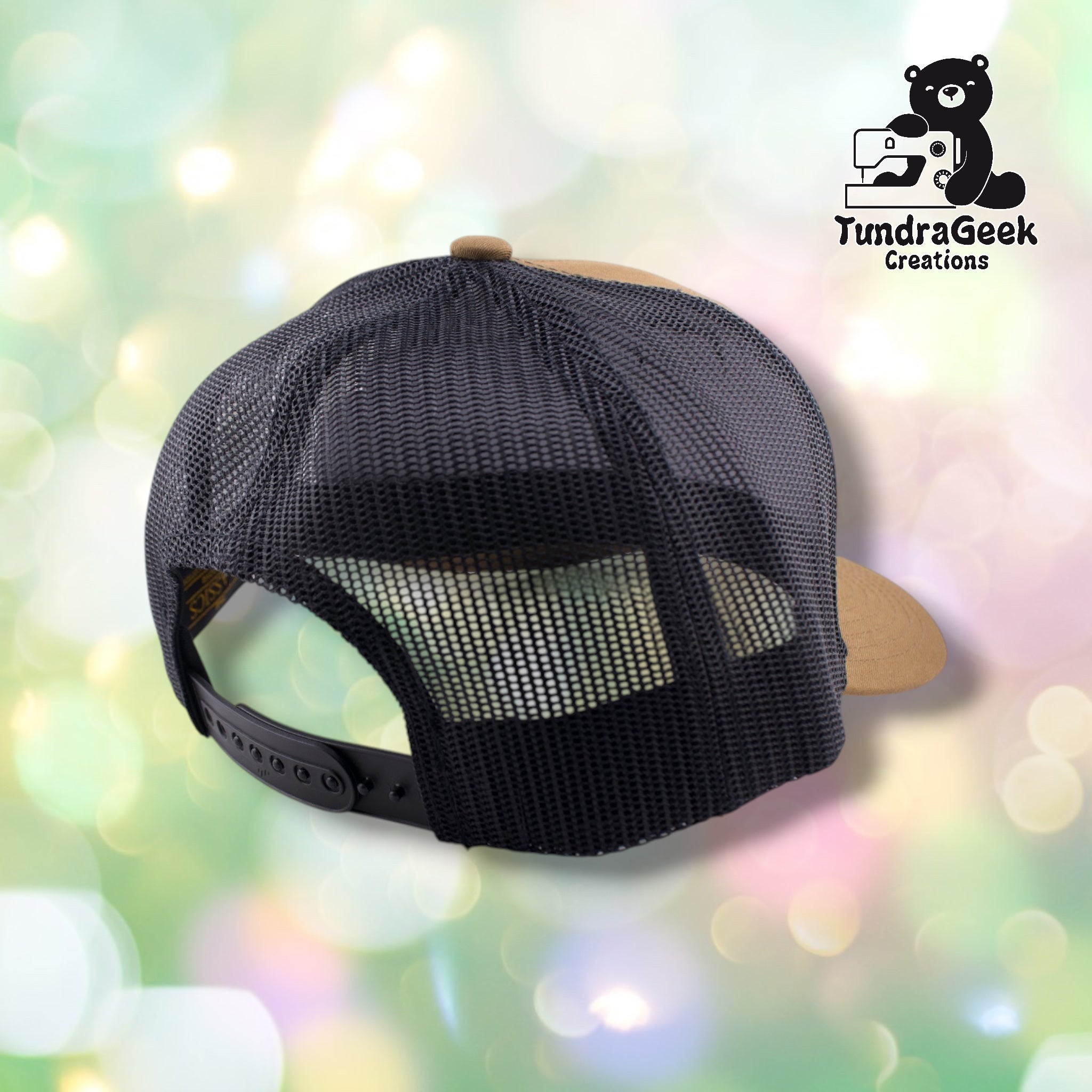 A black mesh trucker cap with tan front panels and black snapback closure, displayed against a soft blurred background.