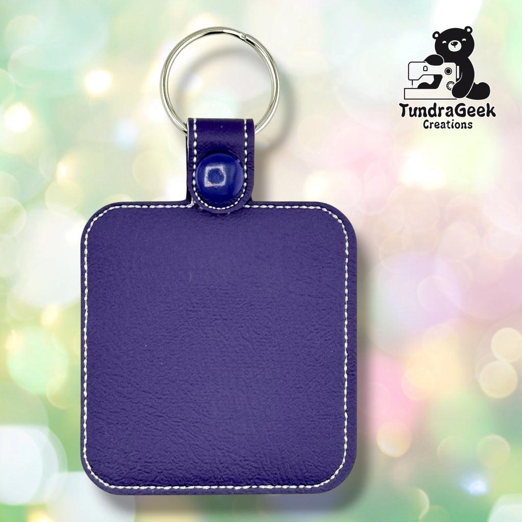 The back of the Do Not Flea badge, plain purple vinyl with white topstitching following the rounded edge. A blue plastic snap and silver split ring are at the top.