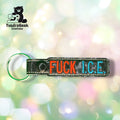 A keychain with the words FUCK I.C.E. embroidered in red and blue letters, with a metal ring, is shown against a blurred, colorful background.