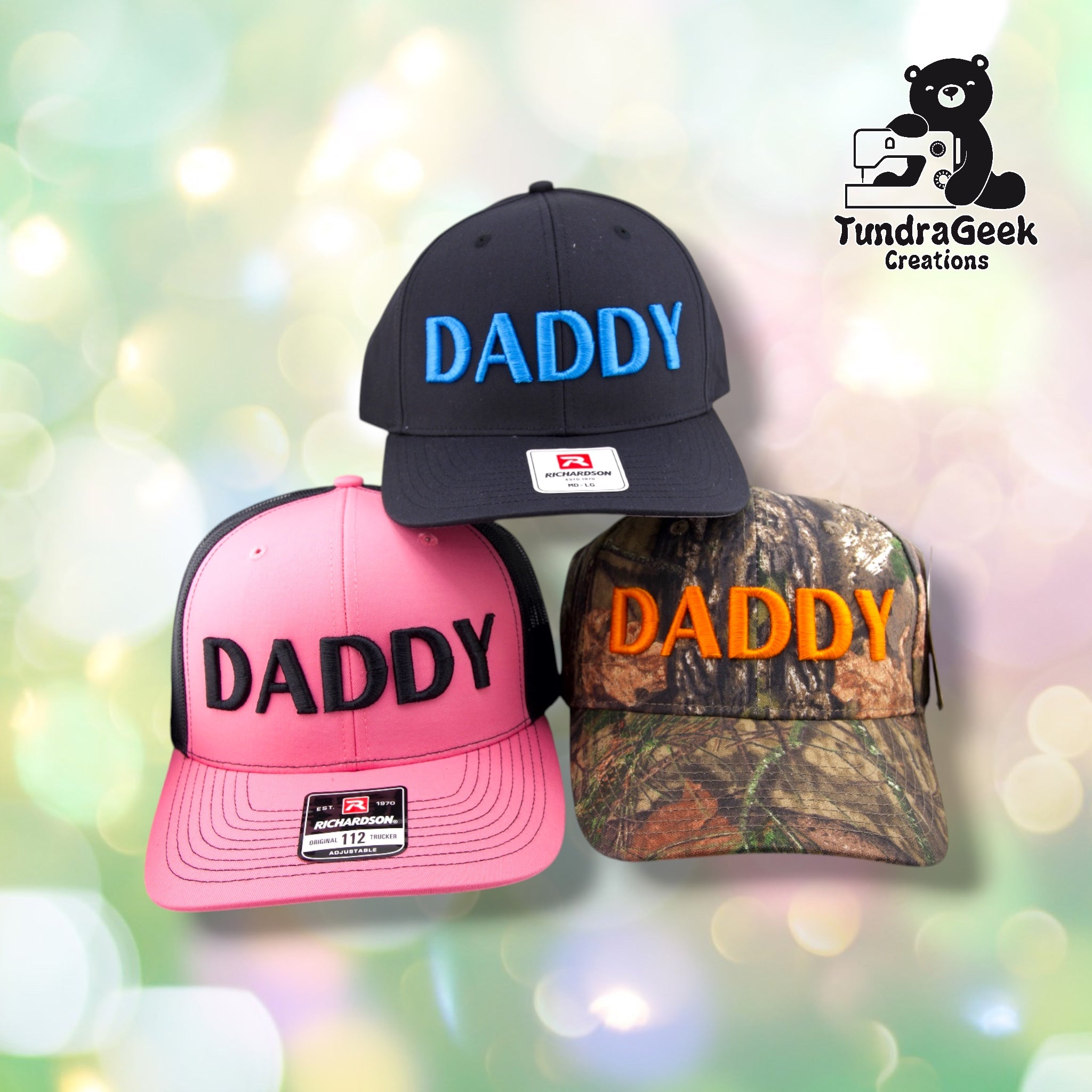 Three embroidered "DADDY" baseball caps in black, hot pink, and camouflage displayed against a blurred green and white bokeh background.