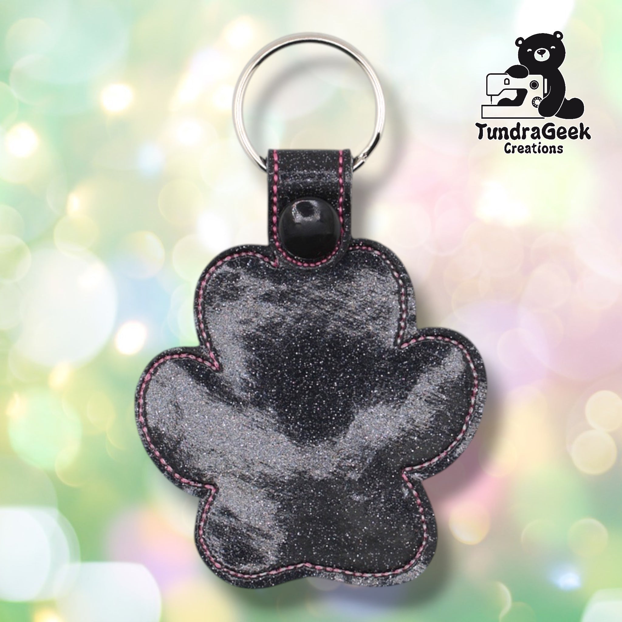 Plain back of the dog heart paw keychain showing black glitter faux leather and pink outline stitching following the paw silhouette. Black plastic snap closure at top. No embroidery on reverse.