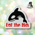 An embroidered patch featuring a black and white orca above the red text 'Eat the Rich' on a white background, shown against a soft pastel bokeh backdrop. A TundraGeek Creations logo is visible in the top right corner.