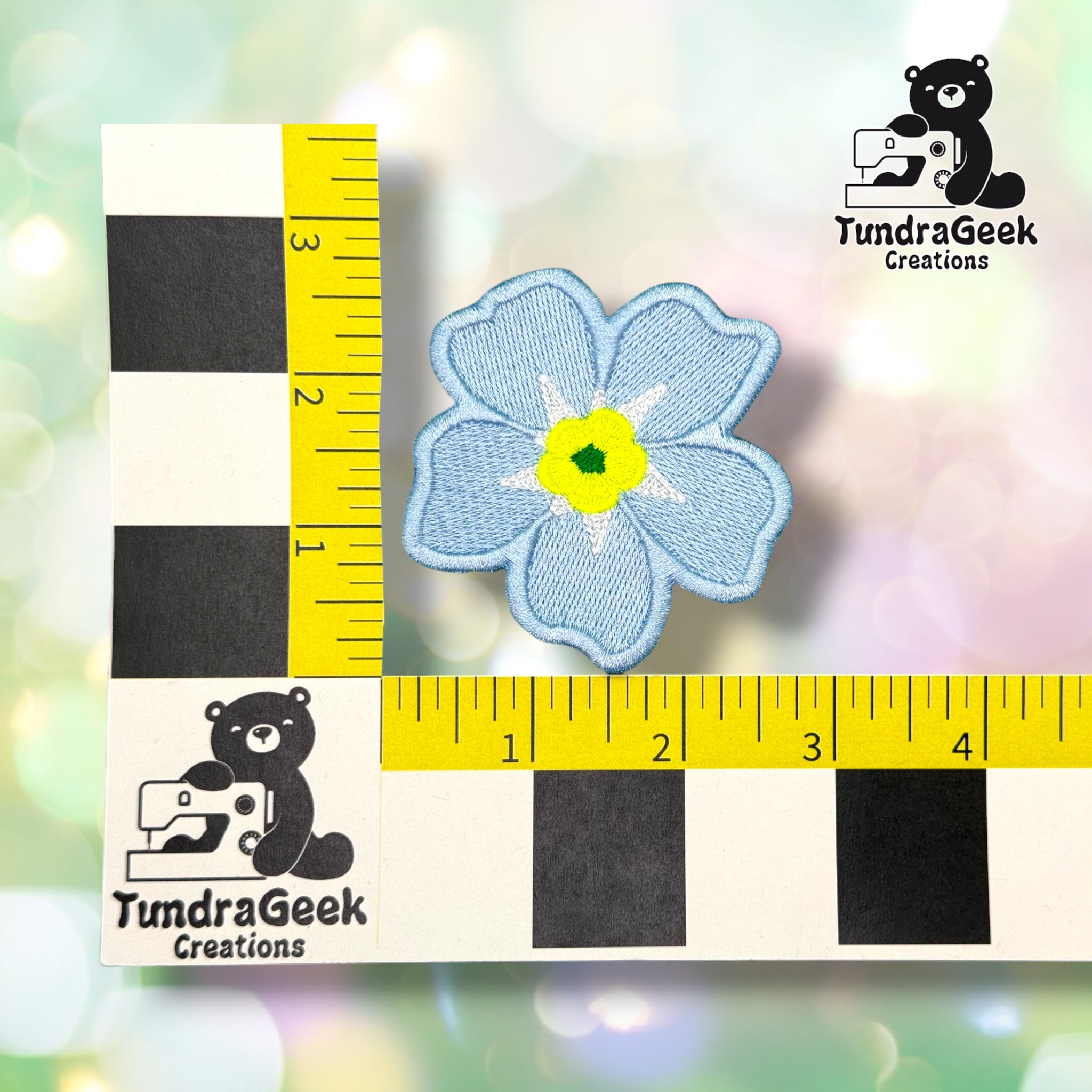 Patch shown against a black-and-white checkered background with yellow rulers for scale, measuring approximately 2.75 inches in diameter.  ---