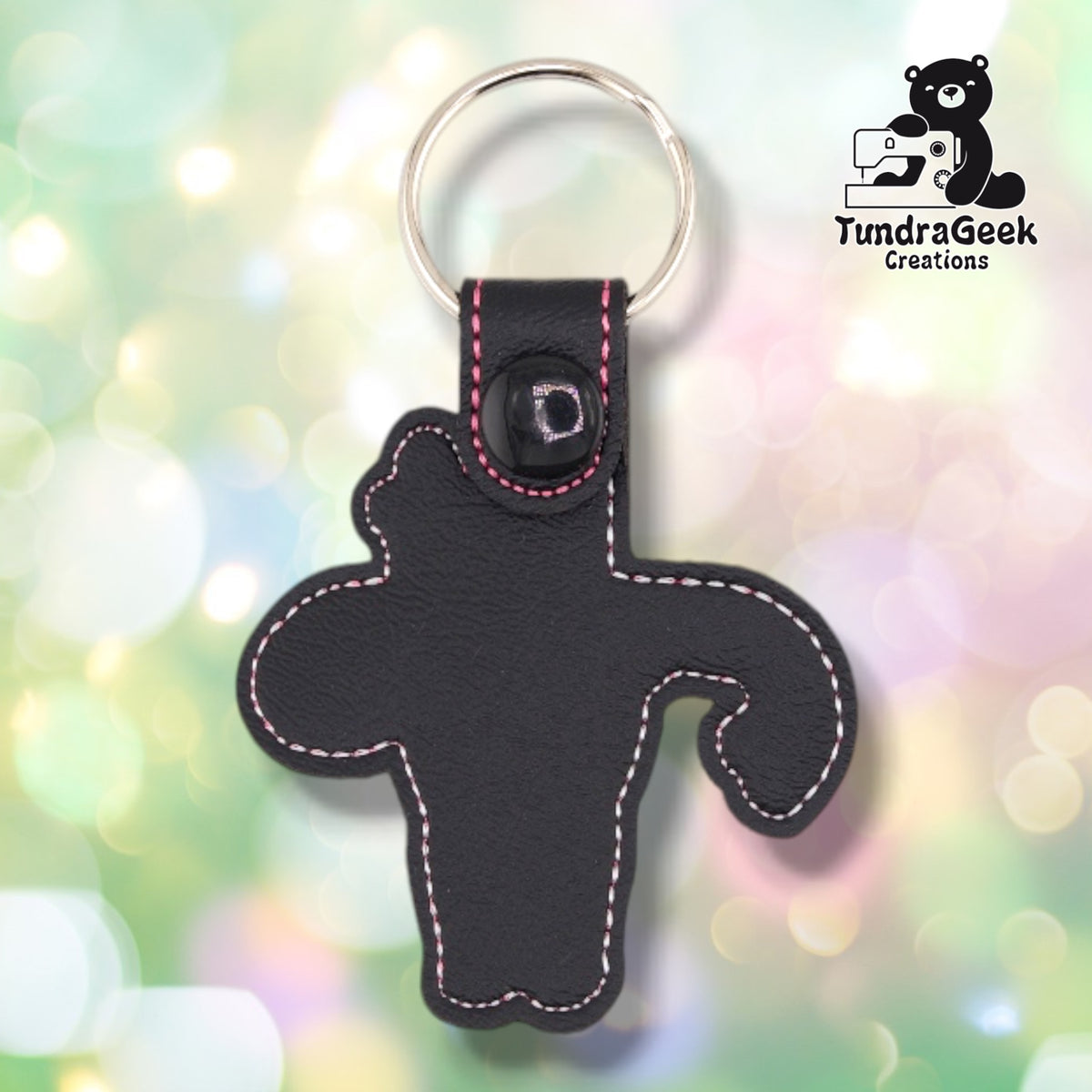 The back of the black colorway, plain black vinyl with pink and white topstitching following the outline of the shape. The black plastic snap and silver split ring are at the top.