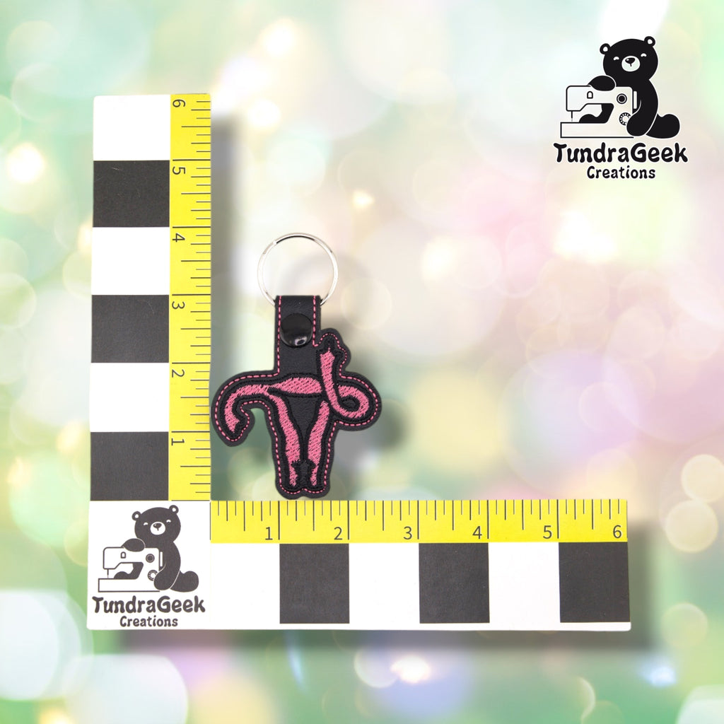 The black colorway photographed against a yellow ruler marked in inches along both edges, for size reference. It measures 4.25 inches tall by 2.5 inches wide including hardware.