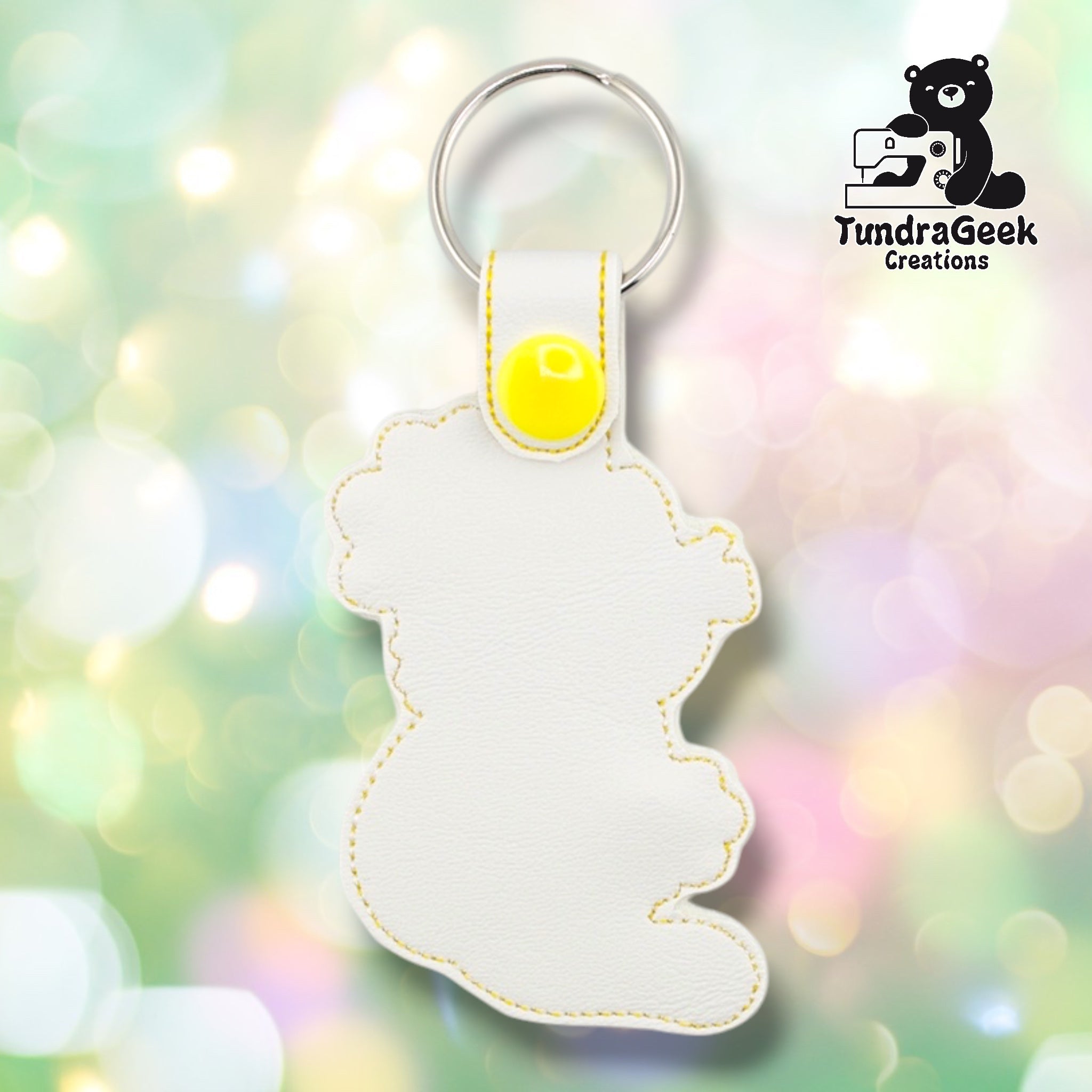 Plain back of the flower kitty keychain showing white faux leather and yellow outline stitching following the cat and flower silhouette. Yellow plastic snap closure at top. No embroidery on reverse.