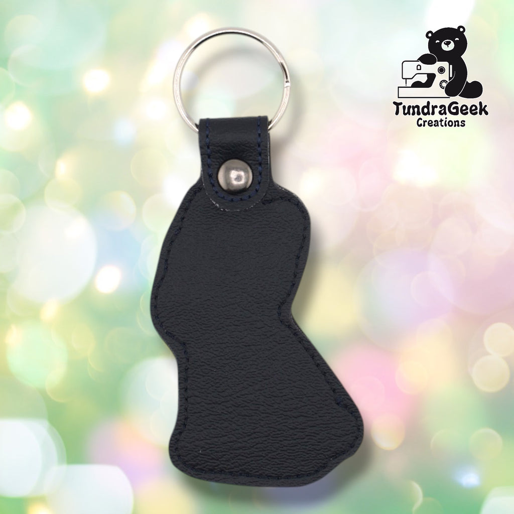Back of a black faux leather French Bulldog keychain. The plain black vinyl back panel shows dark outline stitching following the seated Frenchie silhouette shape. A gunmetal 9mm metal rivet closure secures the tab, with a silver split ring attached above.