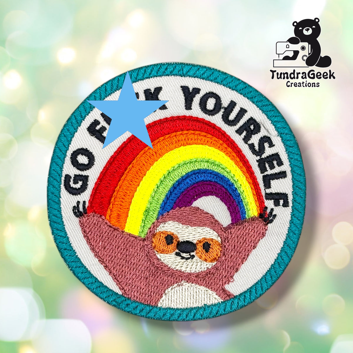 Front view of the patch with a blue star covering the crass middle word of the phrase, for use on platforms or in contexts where the uncensored text isn't appropriate. The visible text reads "GO F[covered]K YOURSELF" arced in black around a rainbow, above a smiling rose-pink sloth hanging from the rainbow's ends.