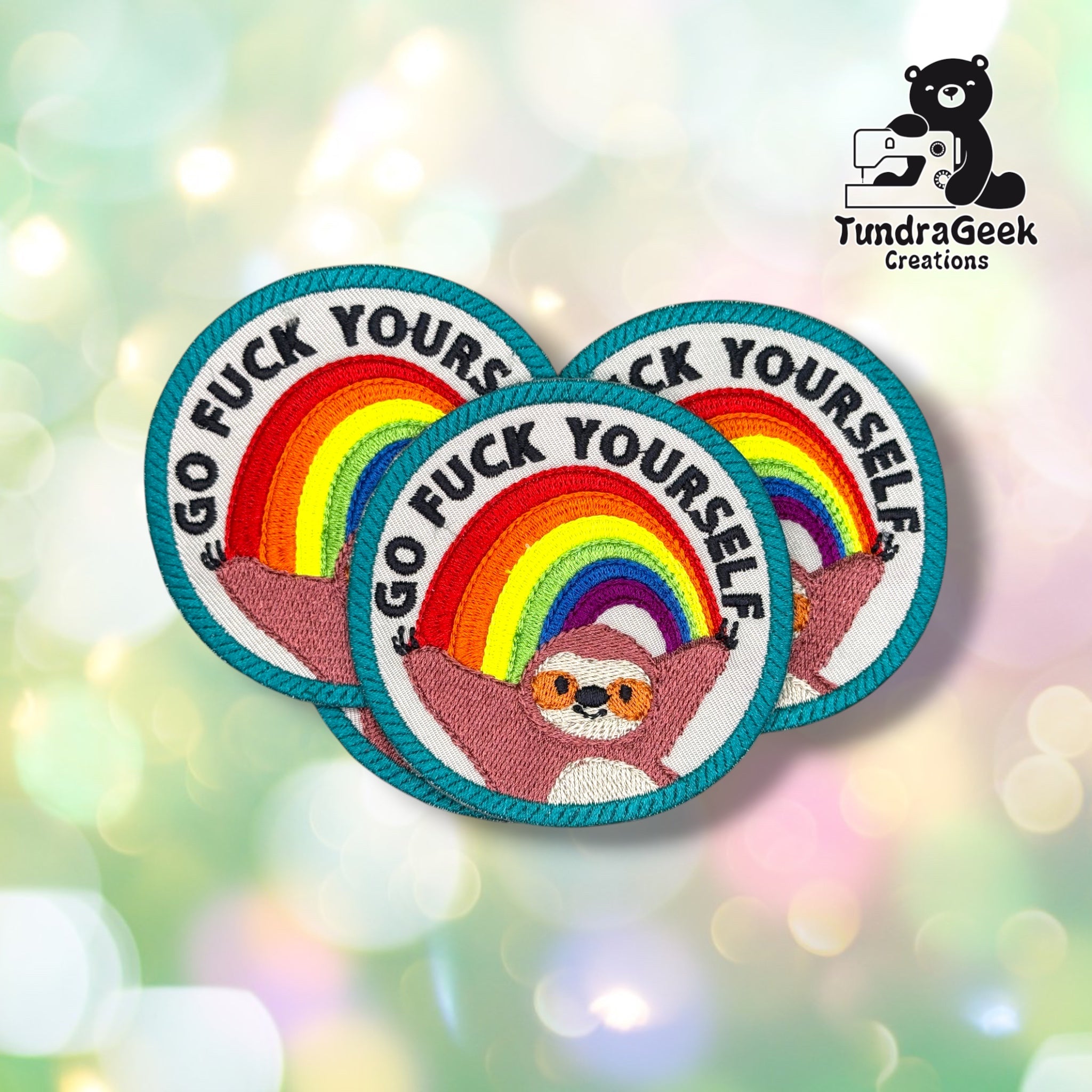 Three identical circular patches fanned out together, each showing the same rainbow-and-sloth design with the phrase embroidered around the border.