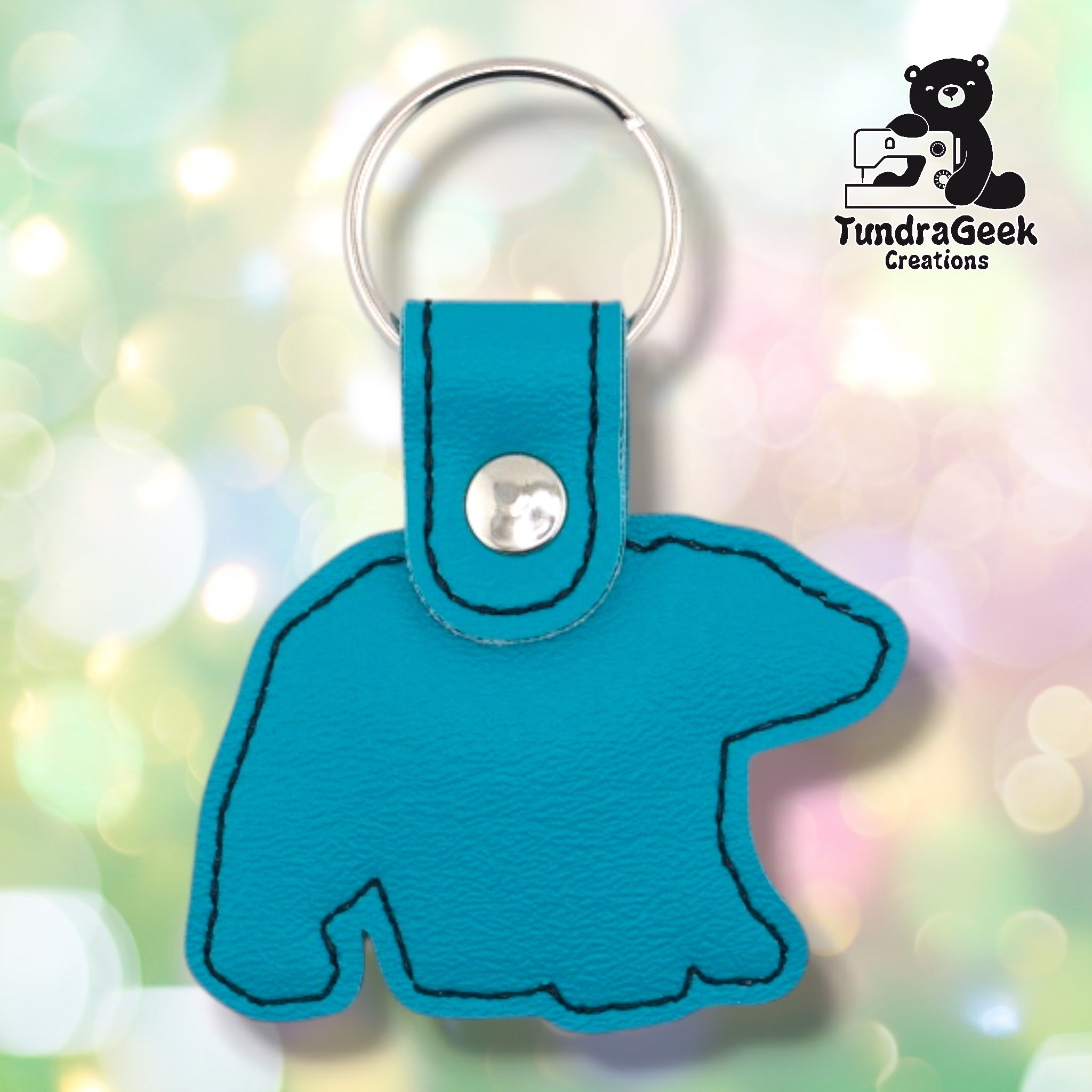 Back of a teal faux leather geometric polar bear keychain. The plain teal vinyl back panel shows dark outline stitching following the bear silhouette shape. A silver 9mm metal rivet closure secures the tab, with a silver split ring attached above.