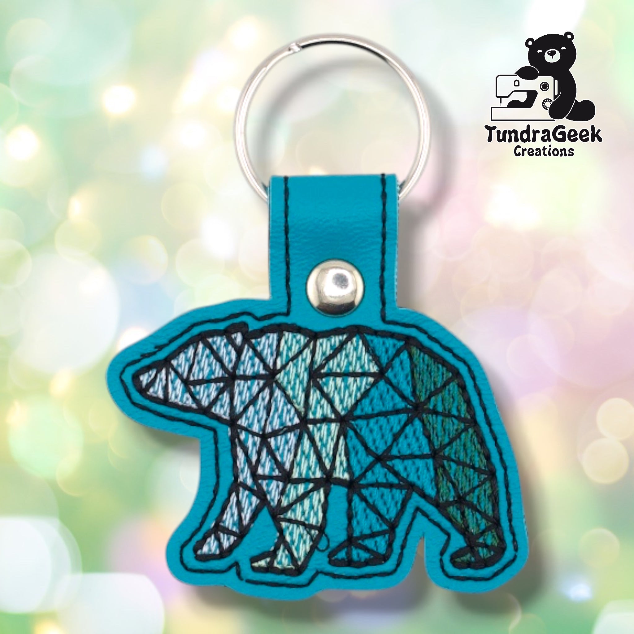 Front of a teal faux leather geometric polar bear keychain. An embroidered low-poly polar bear design fills the bear-shaped vinyl base, with thread color transitioning from light blue and white at the head and shoulders to teal and green toward the hindquarters. Black geometric grid lines define the faceted shapes throughout. A silver 9mm metal rivet closure is visible on the tab, with a silver split ring above.