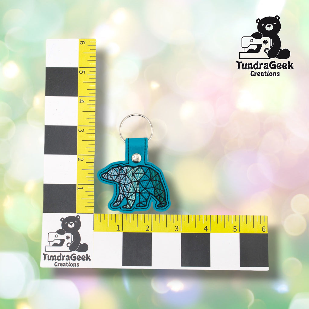 Teal geometric polar bear keychain shown against a TundraGeek Creations L-shaped ruler prop. The keychain body measures approximately 2.75 inches wide by 2.75 inches tall. Total height including tab and split ring is approximately 3.5 inches.