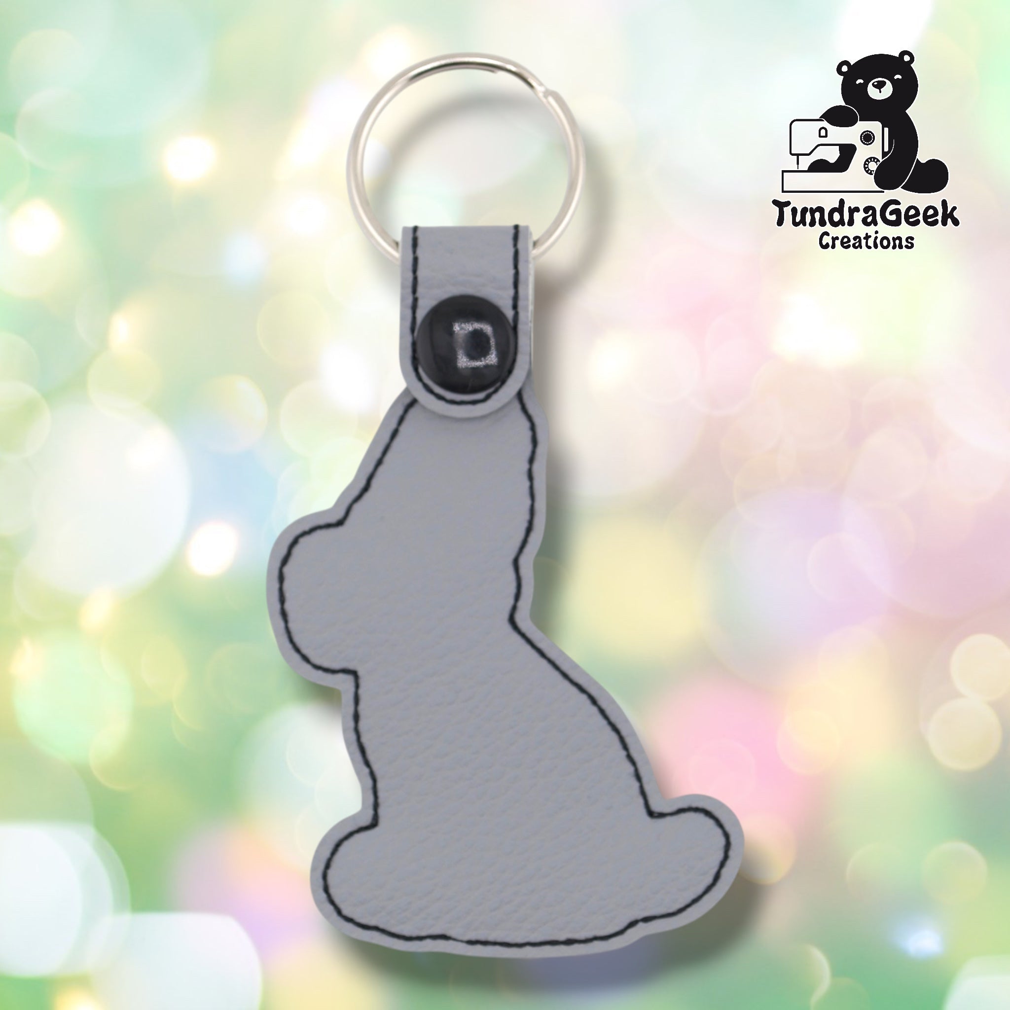 Plain back of the Great Dane keychain showing gray faux leather, black outline stitching following the shape of the seated dog, and black snap closure. No embroidery on reverse.