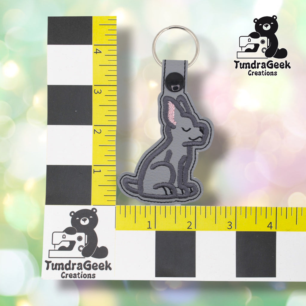 Great Dane keychain positioned against a TundraGeek Creations branded ruler card showing yellow tape measure. Keychain body measures approximately 2.5 inches wide by 3.5 inches tall, not including hardware.