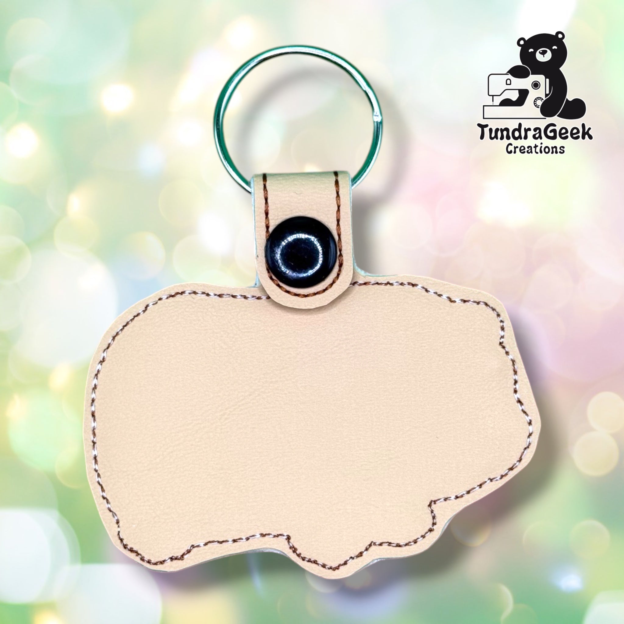 Back of the guinea pig keychain, showing a plain tan vinyl reverse with cream and brown outline stitching following the guinea pig silhouette. Black snap closure and green metal split ring at top.