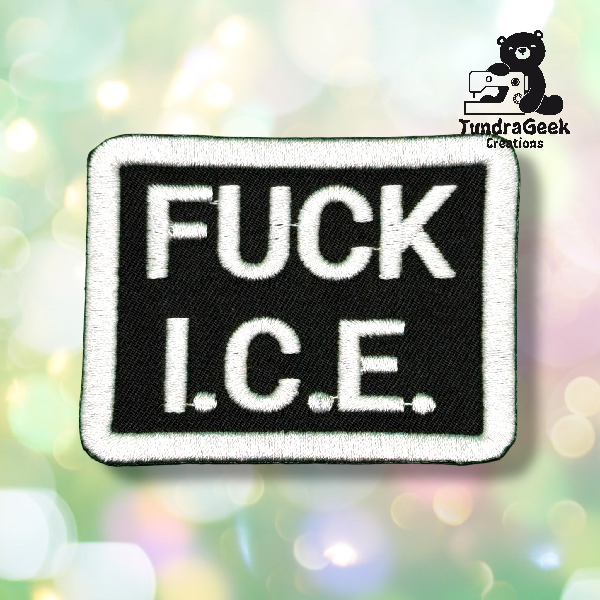 A rectangular black patch with bold white text that reads FUCK I.C.E. appears on a blurred multicolored background. The TundraGeek Creations logo is in the top right corner.