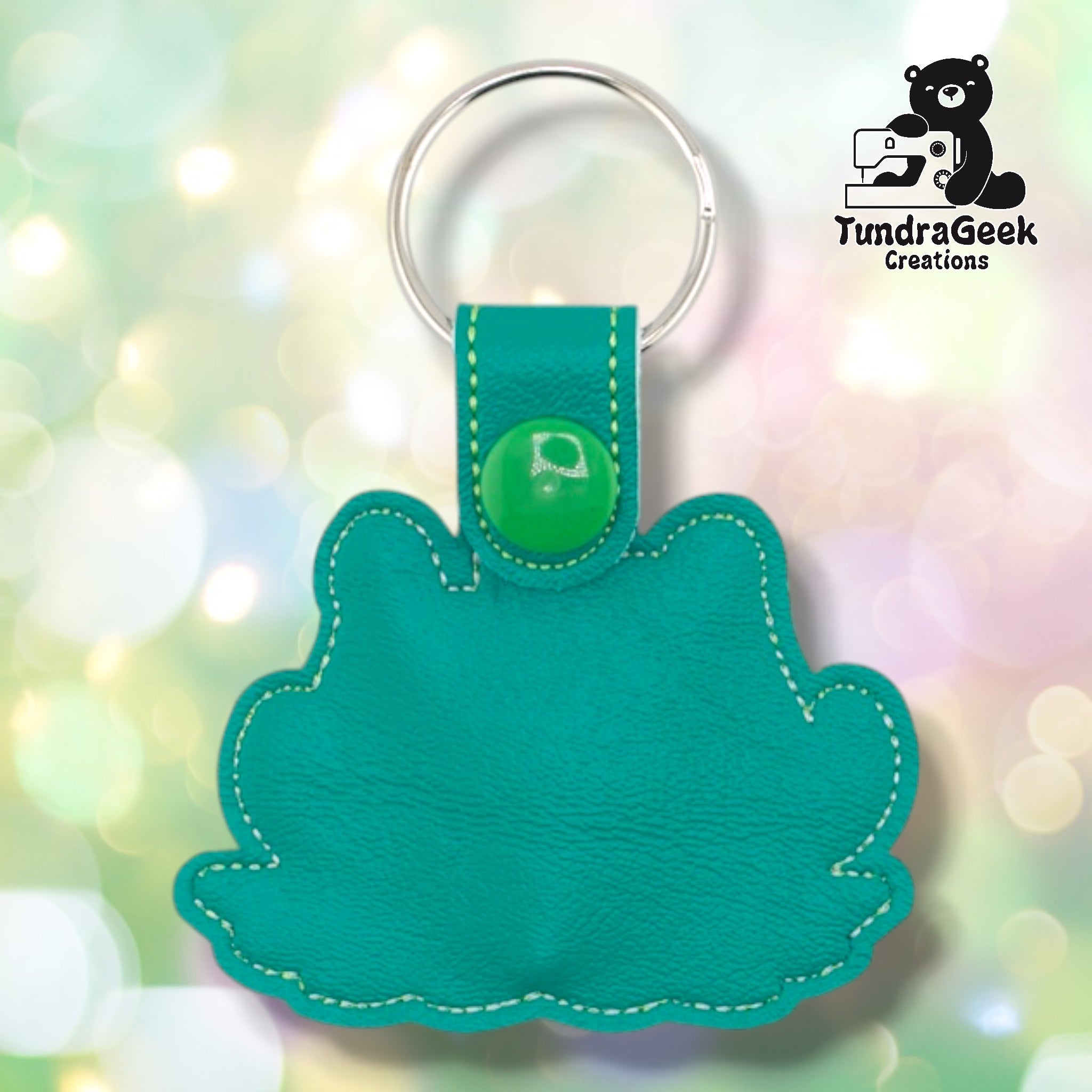 Plain back of the killer plant keychain showing teal faux leather and yellow-green outline stitching following the plant silhouette. Green plastic snap closure at top. No embroidery on reverse.
