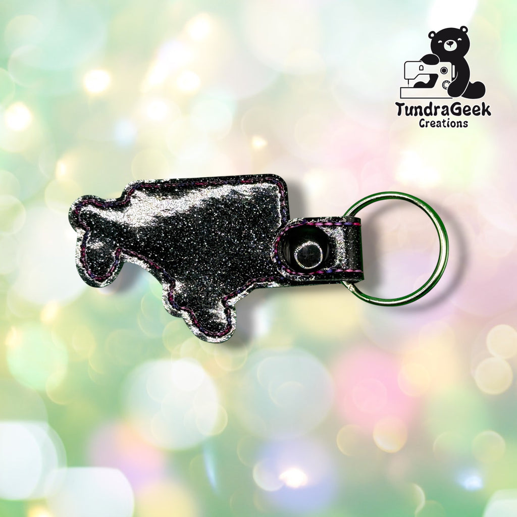 Back view of the keychain showing the plain black glitter vinyl backing and black plastic snap closure. No embroidery visible from this side.