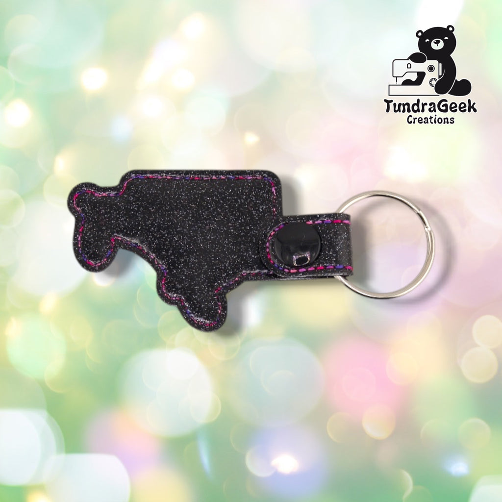 Back view of the keychain, plain black glitter vinyl with the black plastic snap closure and silver split ring at the top. No embroidery visible from this side.