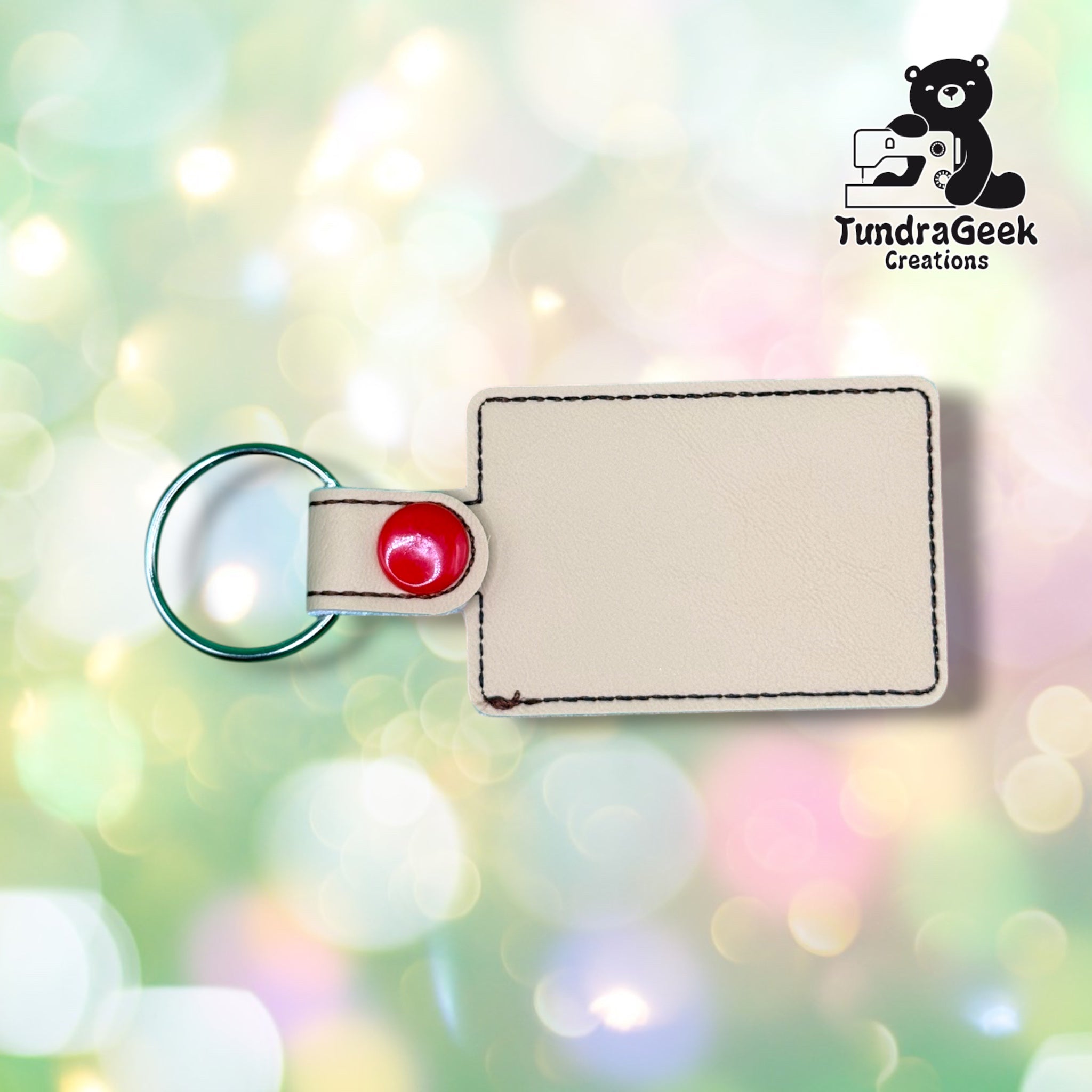 Back view of the keychain showing the plain tan vinyl backing and red plastic snap closure tab. No embroidery visible from this side.