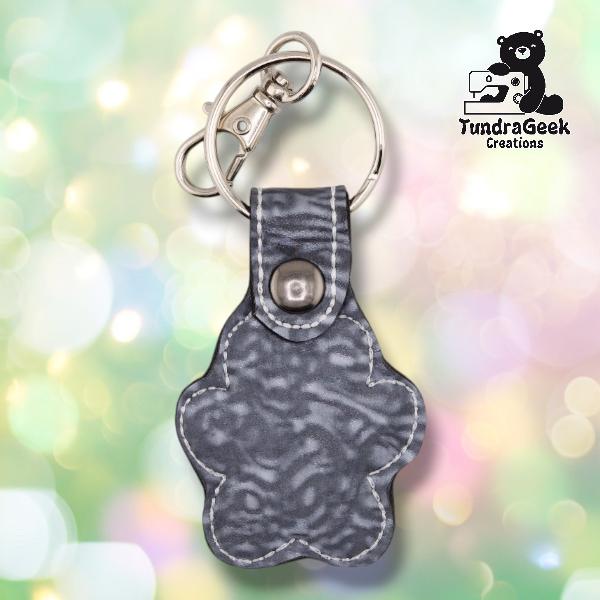 The back of the Silver colorway paw print keychain, showing the plain marbled grey vinyl backing and metal rivet closure at the top.
