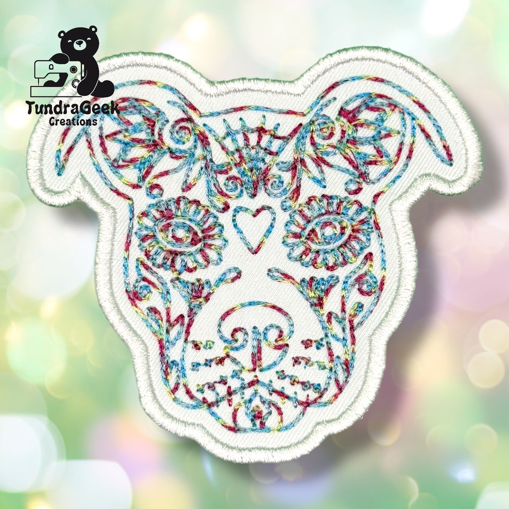 Embroidered patch featuring a colorful, ornate dog face design on a white background. TundraGeek Creations logo appears in the top left corner.