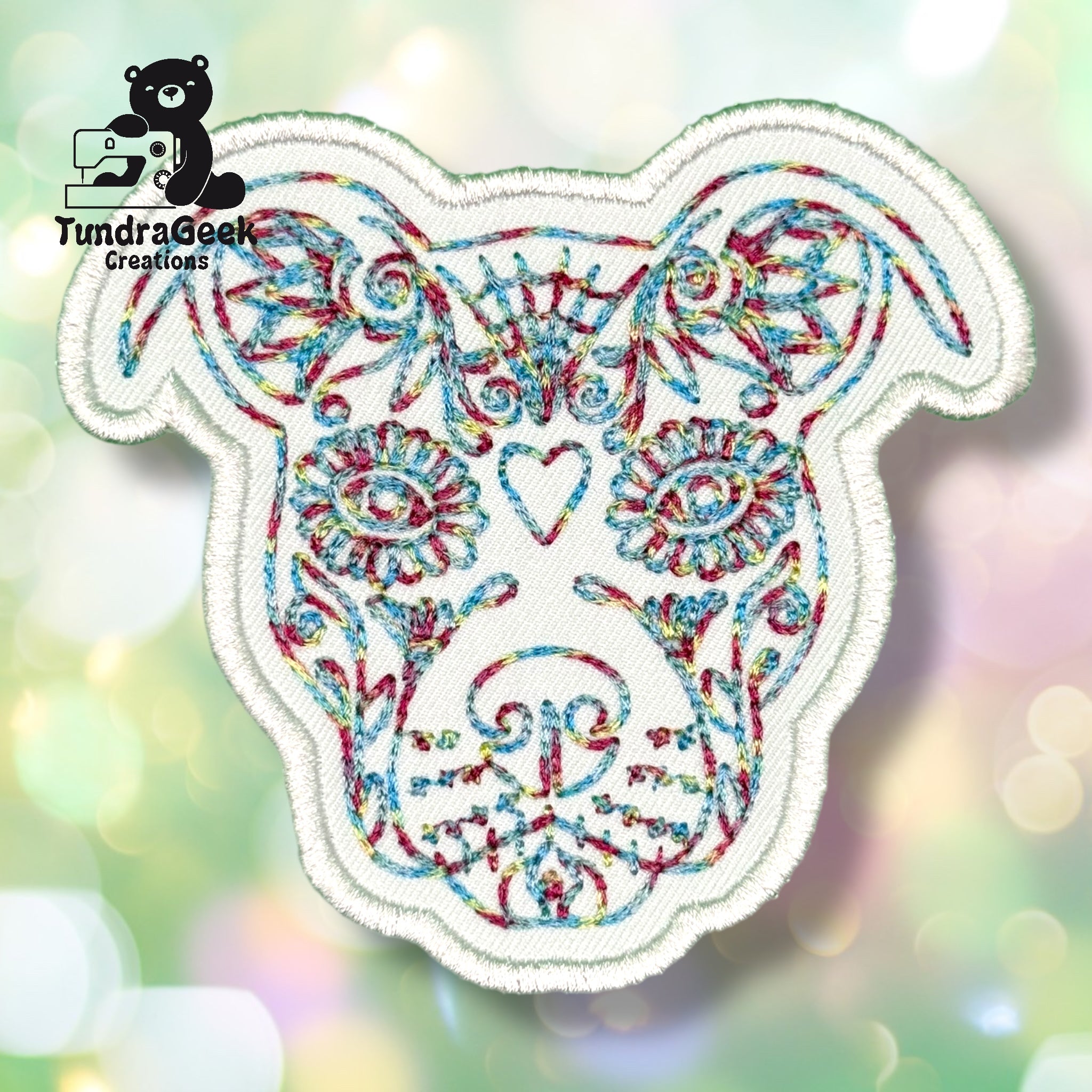 Embroidered patch featuring a colorful, ornate dog face design on a white background. TundraGeek Creations logo appears in the top left corner.