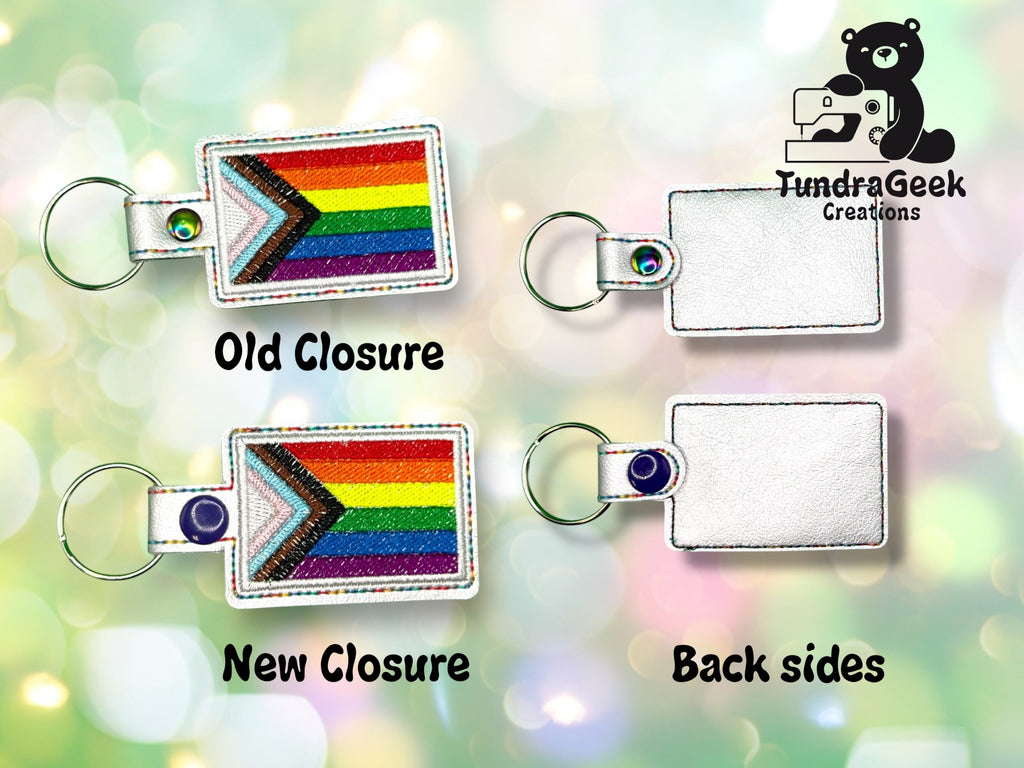 Four rectangular keychains with rainbow pride flag fronts and silver backs are shown. Two have old and new closures, and the TundraGeek Creations logo is in the upper right corner.