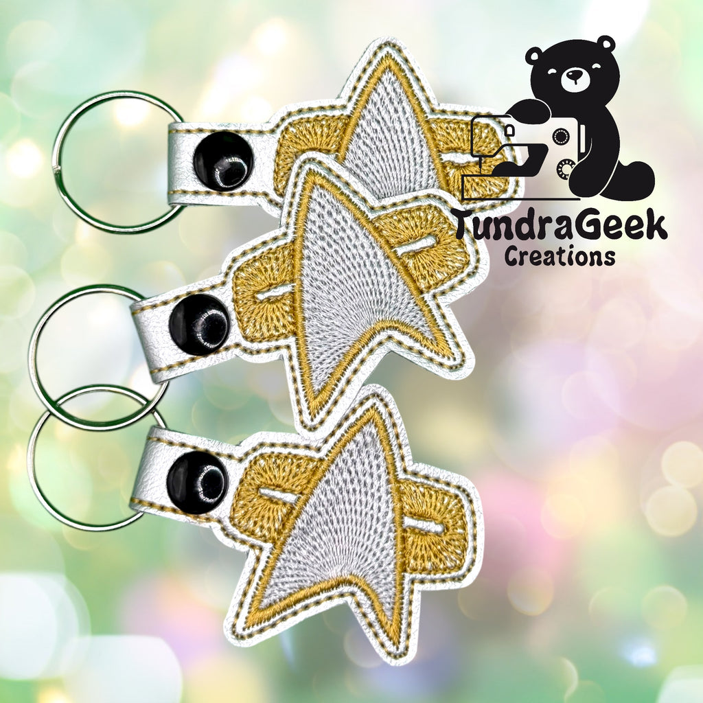 Three embroidered keychains shaped like the Star Trek insignia with gold and silver thread, displayed next to the TundraGeek Creations logo.