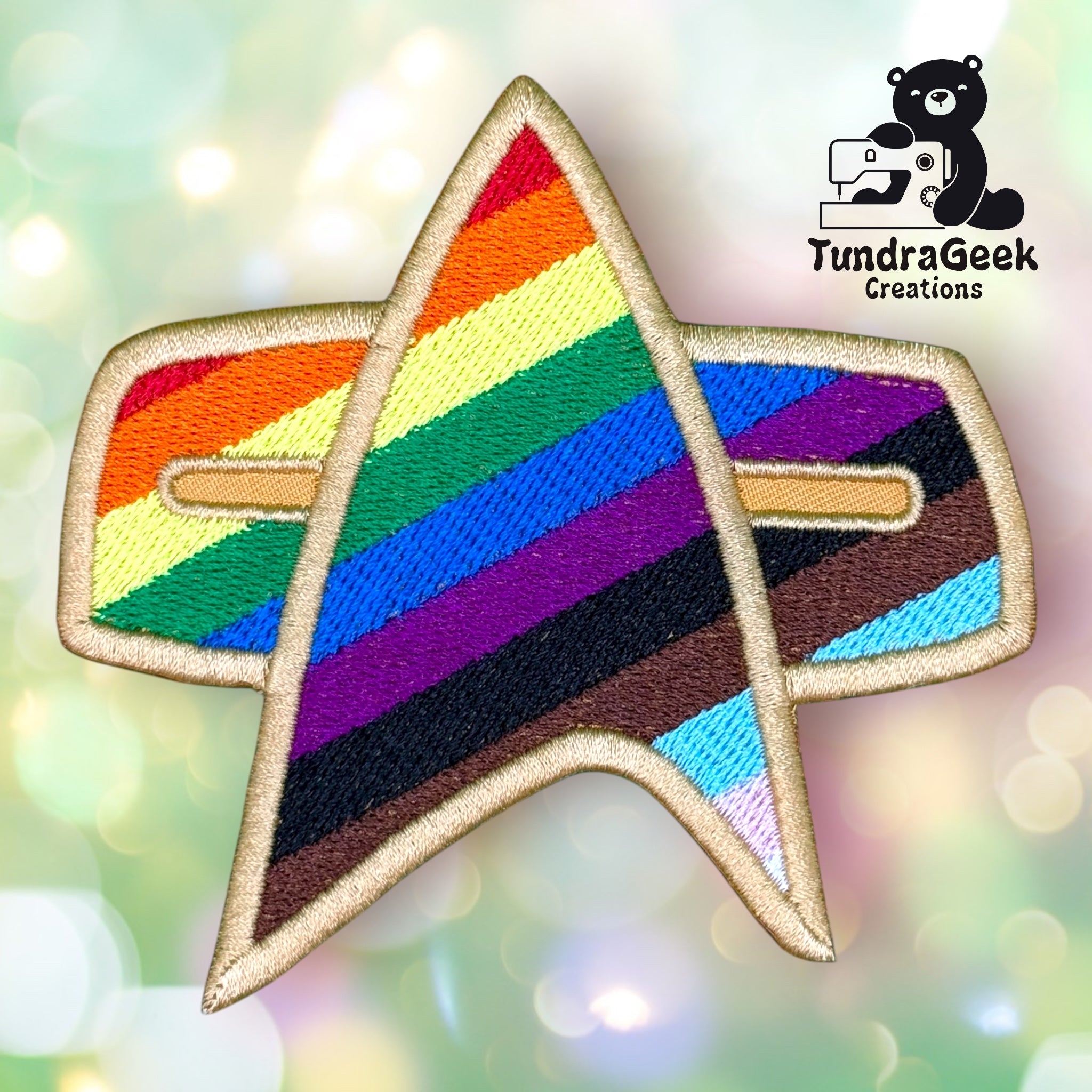 An embroidered Star Trek insignia patch features the Pride flag colors, including black and brown stripes. The TundraGeek Creations logo with a bear and a sewing machine appears in the corner.