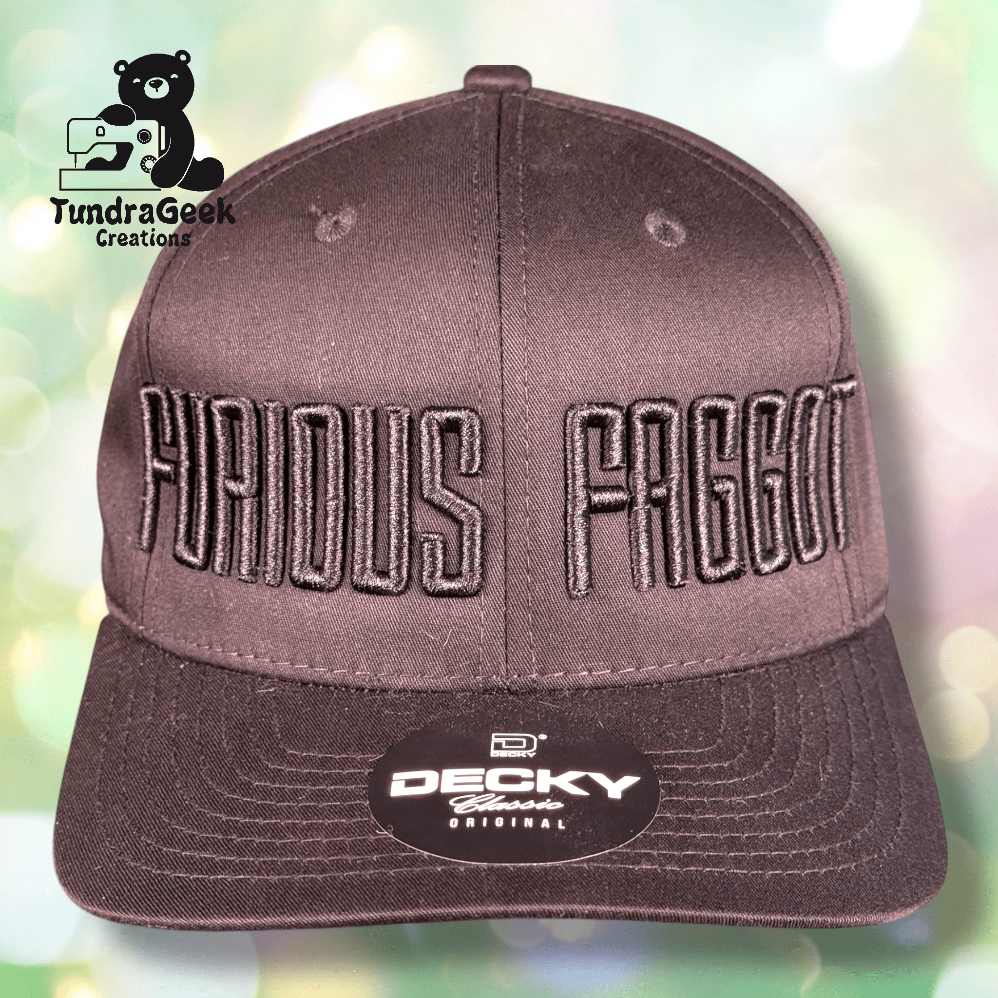 A brown DECKY snapback hat with bold embroidered text reading FURIOUS FAGGOT on the front. TundraGeek Creations logo is in the top left corner of the image.