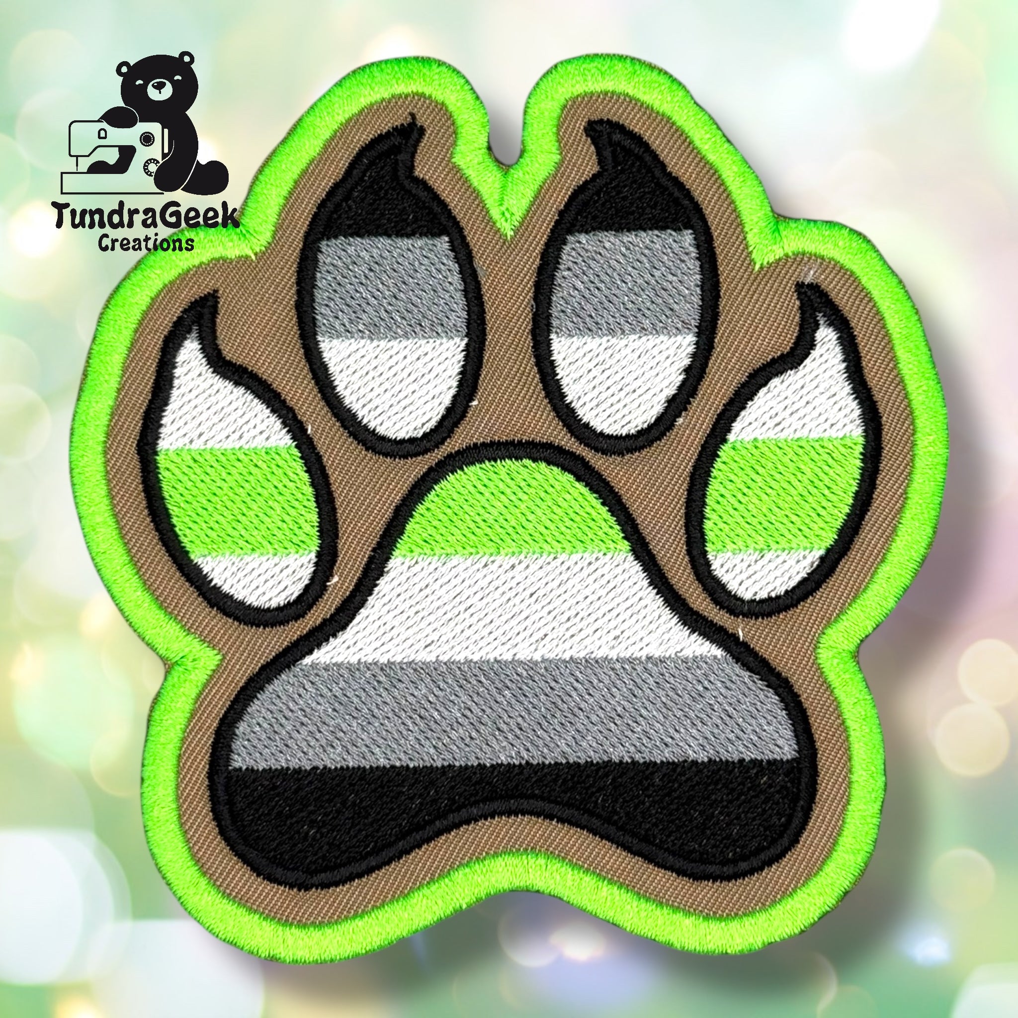 An embroidered paw-shaped patch with a canine paw design on a bright lime green background. The flag stripes in black, gray, white, and green run horizontally across the patch. The claws and paw pads are outlined in black with visible claw detail. Bright lime green border edging.