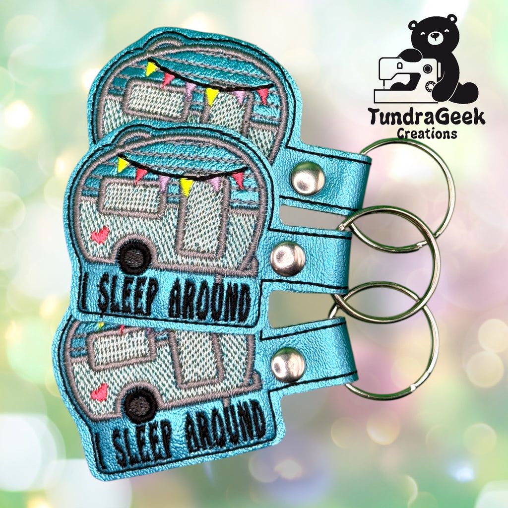 Three embroidered keychains with a camper van design and the text I SLEEP AROUND, displayed with the TundraGeek Creations logo in the corner.