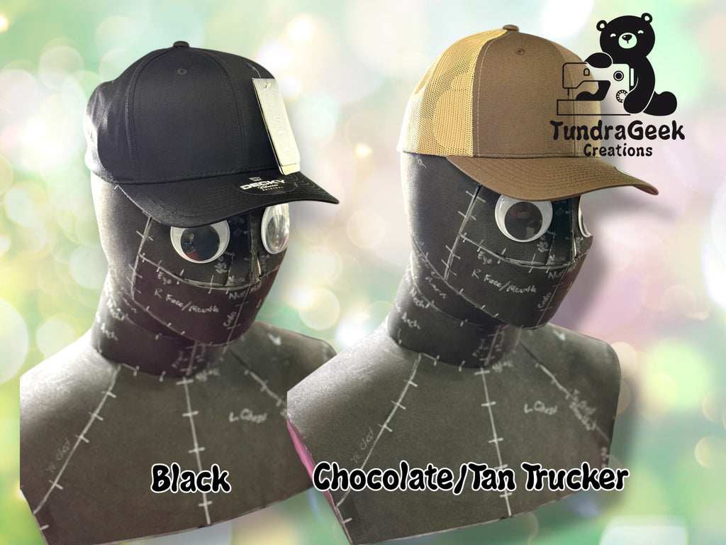 Two mannequin heads display caps: one black and one brown trucker style. TundraGeek Creations logo and bear sewing graphic appear in the top right corner.