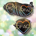 A set of black heart-shaped stickers with the text 'DRAG FOR A CAUSE' and 'DFAC' in white, outlined with a rainbow gradient border, shown on a soft green and gold bokeh background. A Tundra Geek Creations logo is visible in the top right corner.