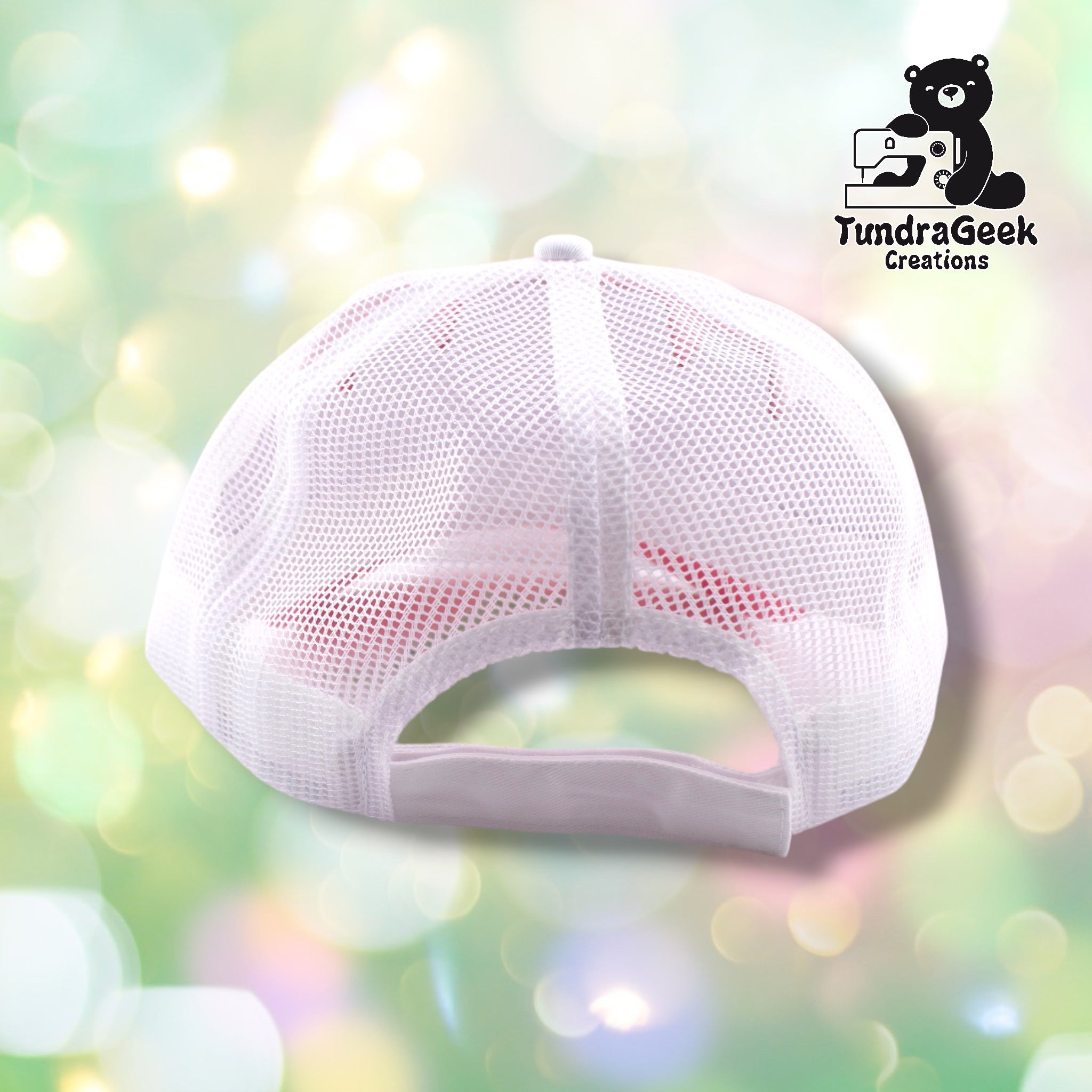 A white mesh baseball cap from the back with pink panels on the front, displayed against a soft pastel bokeh background.