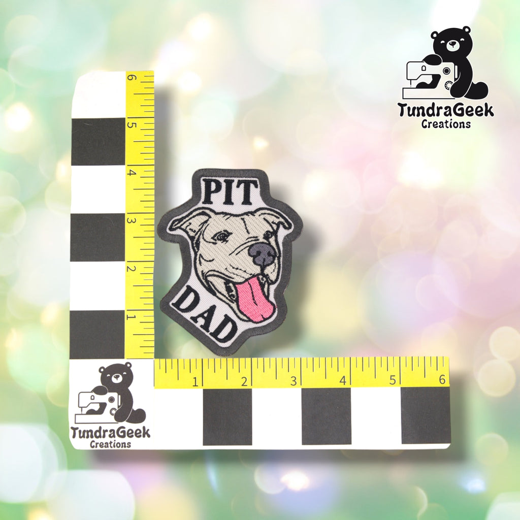 The Pit Dad patch photographed against a yellow ruler marked in inches along both edges, for size reference. It measures just under 4 inches tall by 3 inches wide.